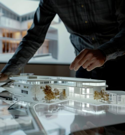 A designer carefully works on an architectural model displayed on a light table, with a detailed building image projected in the background.